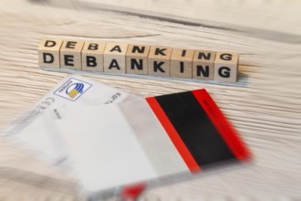 Debanking symbol: Letter cubes in front of a cut bank card show the word DEBANKING