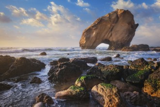 Penedo do Guincho, a large boulder rock arch at Praia da Santa Cruz, Portugal, with ocean waves and