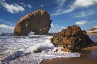 Penedo do Guincho, a large boulder rock arch at Praia da Santa Cruz, Portugal, with ocean waves and