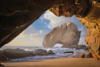Penedo do Guincho, a large boulder rock arch at Praia da Santa Cruz, Portugal, with ocean waves and
