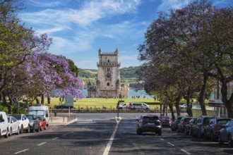 Beautiful Belem Tower stands tall over purple blooming jacarandas on the Tagus River, capturing