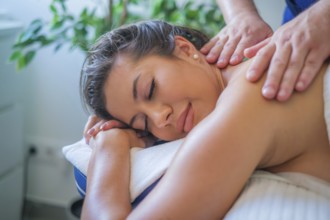 A woman receives a soothing back massage from a professional therapist using oil. The tranquil spa