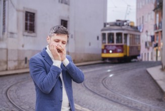 Man musician in a blue blazer and white sweater playing blues on a harmonica with eyes closed,