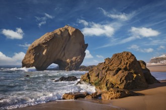 Penedo do Guincho rock at Praia da Santa Cruz as waves crash against the sandy shore during a