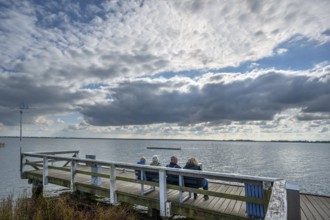 Tourists sitting on a bench at Wustrow harbour, DarÃŸ, Mecklenburg-Western Pomerania, Germany