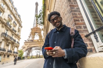 African man enjoying his travel experience in paris, standing on the street with the eiffel tower