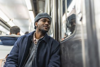 Young man sitting on a subway train, looking thoughtfully out the window during his daily commute,