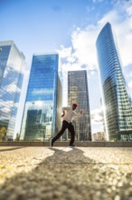 Man running with energy and freedom against a backdrop of modern glass skyscrapers, symbolizing