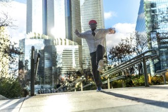 Energetic black man in a red hat and white shirt dancing with joy on an outdoor staircase,