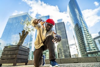 Young black man performing a dynamic street dance pose, capturing urban culture and a cool