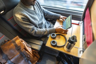 Man finding comfort and productivity while traveling for business, utilizing his tablet and staying