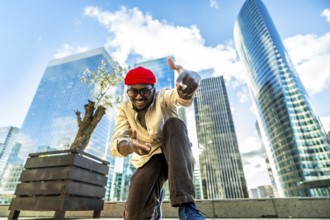 Happy young man wearing a red beanie and glasses, smiling and gesturing towards the camera,