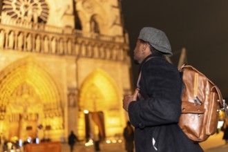 Young man traveler with a backpack looking up at the majestic gothic architecture of notre dame