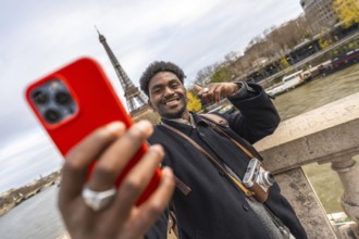 Young black man smiling and taking a selfie with a smartphone, capturing a memorable travel moment