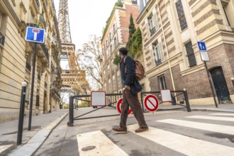 Adult man traveling in paris, france, carrying a backpack and walking across a zebra crossing with