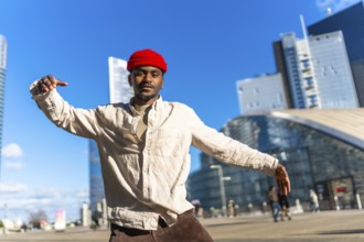 Young black man showing movement and expressing himself through dance in an urban setting with