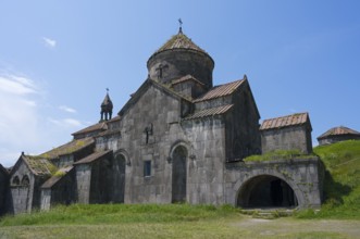 Stone monastery with several structures and domes in front of a wide meadow, Haghpat monastery,