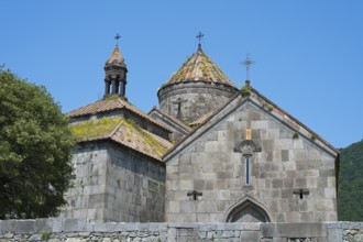Massive stone church towers with cross-decorated roofs surrounded by a clear sky, Haghpat