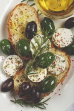 A plate with a snack, ciabatta bread with cheese and olives, olive oil, spices and herbs, top view,