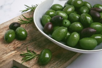 Chalkidiki olives, classic Greek green olives, in a bowl on a cutting board, top view, without