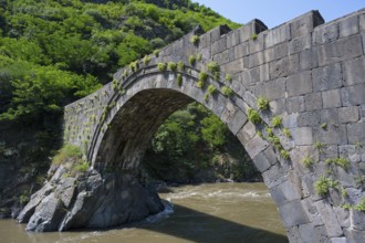 Old stone bridge with vegetation surrounded by a river in natural surroundings, Sanahin bridge