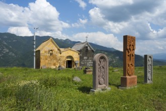 Church with stone sculptures in a green mountain landscape under a cloudy sky, Crossstones,