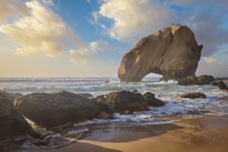 Penedo do Guincho, a large boulder rock arch at Praia da Santa Cruz, Portugal, with ocean waves and