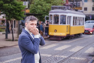 Man musician in a blue blazer and white sweater playing blues on a harmonica with eyes closed,