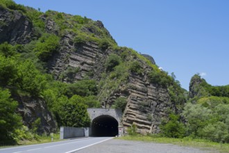A tunnel in a rocky, green landscape under a clear blue sky, road tunnel, Debed gorge, Lorikeet