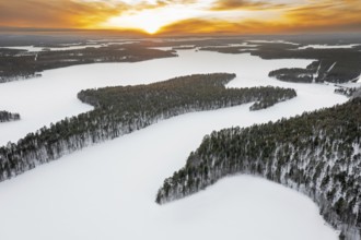 Aerial view over forest and snow covered frozen LahnaselkÃ¤ lake in Kuusamo in winter, Koillismaa,