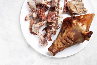 Roast pork head, with remnants of bones and meat, on a white platter, no people, close-up