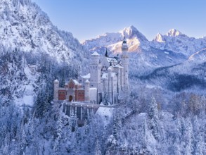 Neuschwanstein Castle nestled in snow, surrounded by snow-covered mountains and forests. Fairytale