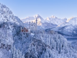 Neuschwanstein Castle rises majestically in a secluded winter landscape surrounded by mountains and