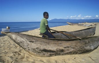 Local boy sitting on a dugout near Kande Beach on Lake Malawi, Malawi, Africa, July 2000, vintage,