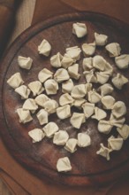 Traditional Turkish dumplings, raw, on a cutting board, top view, no people