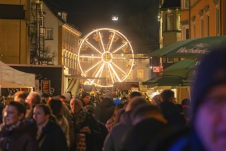 A night-time Christmas market with many visitors and an illuminated Ferris wheel, Christmas market