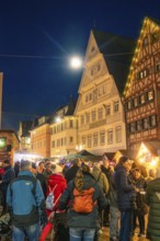 Evening Christmas market with illuminated half-timbered houses and crowd of people in the center,