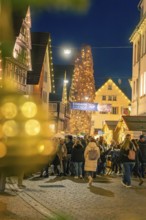 Festive night atmosphere at a Christmas market with illuminated Christmas tree and crowd, Christmas