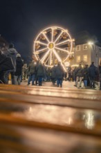 People come together to enjoy an illuminated Ferris wheel at night, Christmas market 2025, Nagold,