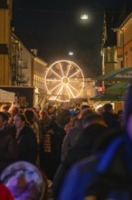 Crowd of people in front of an illuminated Ferris wheel at a municipal Christmas market, Christmas