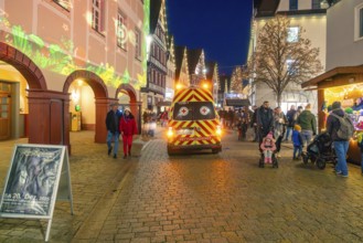 Busy Christmas market at night with rescue service vehicle and festive lighting, Christmas market