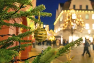 Golden Christmas ball on a pine branch with blurred city lighting in the background, Christmas