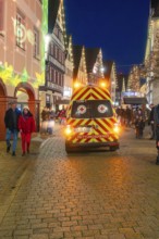Night view of an emergency service vehicle at a busy and festive Christmas market, Christmas market