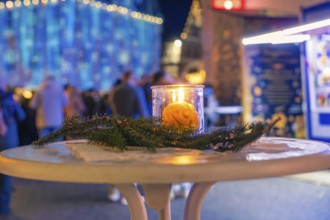 A burning candle on a decorated table at night at a Christmas market, Christmas market 2025,