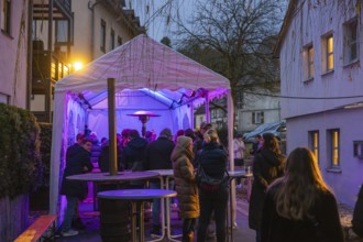 People gather under an illuminated canopy at night, Aidlingen Christmas market, Böblingen district,