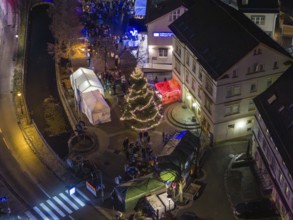Market scene at night with Christmas tree, festive lights and people near tents, Aidlingen