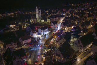 Nighttime city view with decorated Christmas market, church and illuminated streets in a small