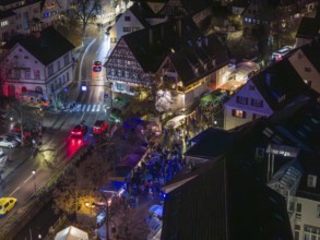 Aerial view of a busy Christmas market at night with illuminated half-timbered houses and crowds of