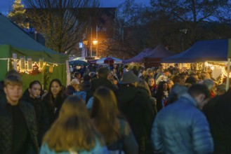 Crowd of people at various market stalls at night, Aidlingen Christmas market, Böblingen district,
