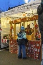 Christmas market stand with glowing decorations and people in front of it, Aidlingen Christmas